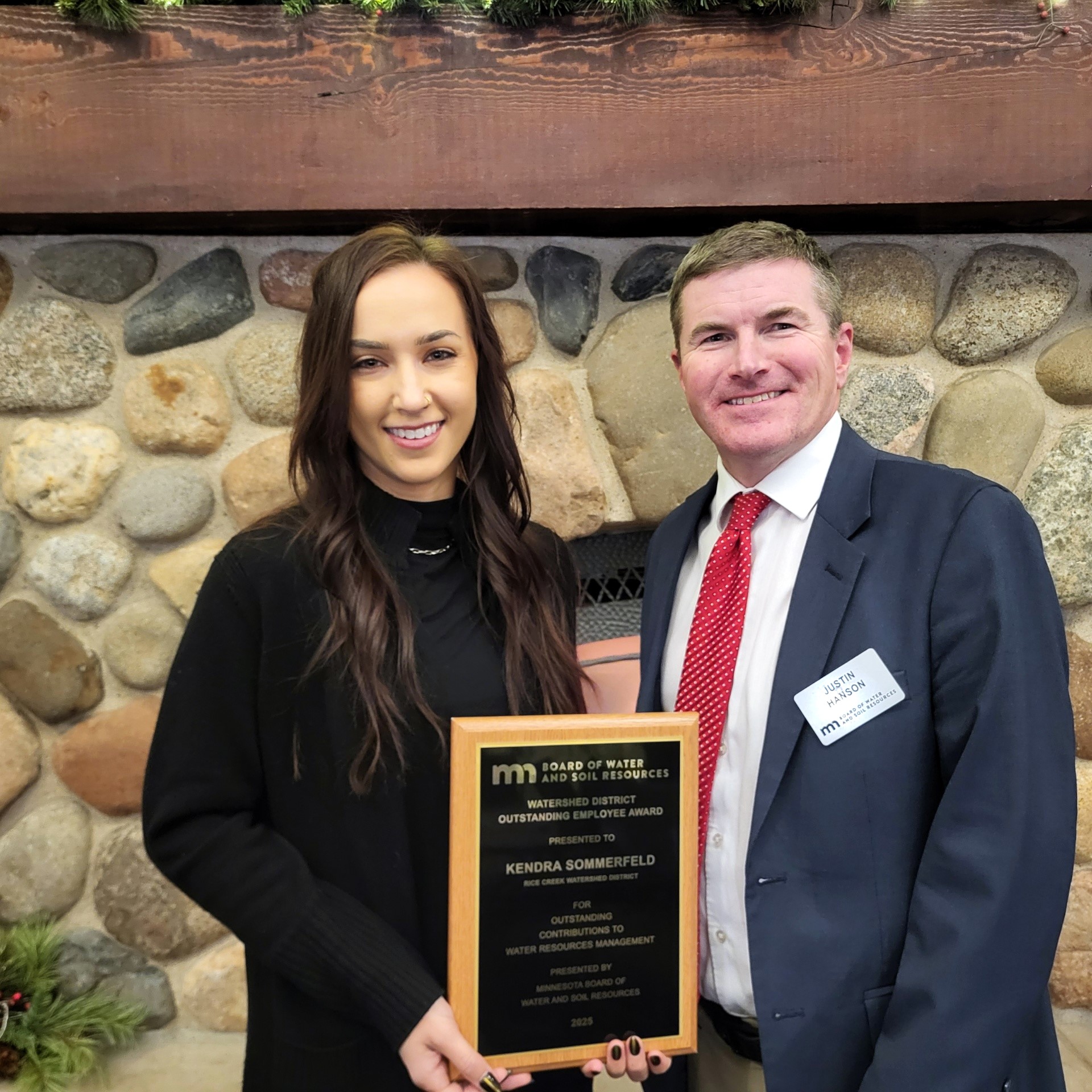 A woman holding an award stands next to a man in a suit