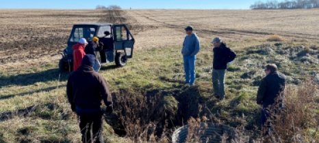 A small group of people stands at the edge of a field